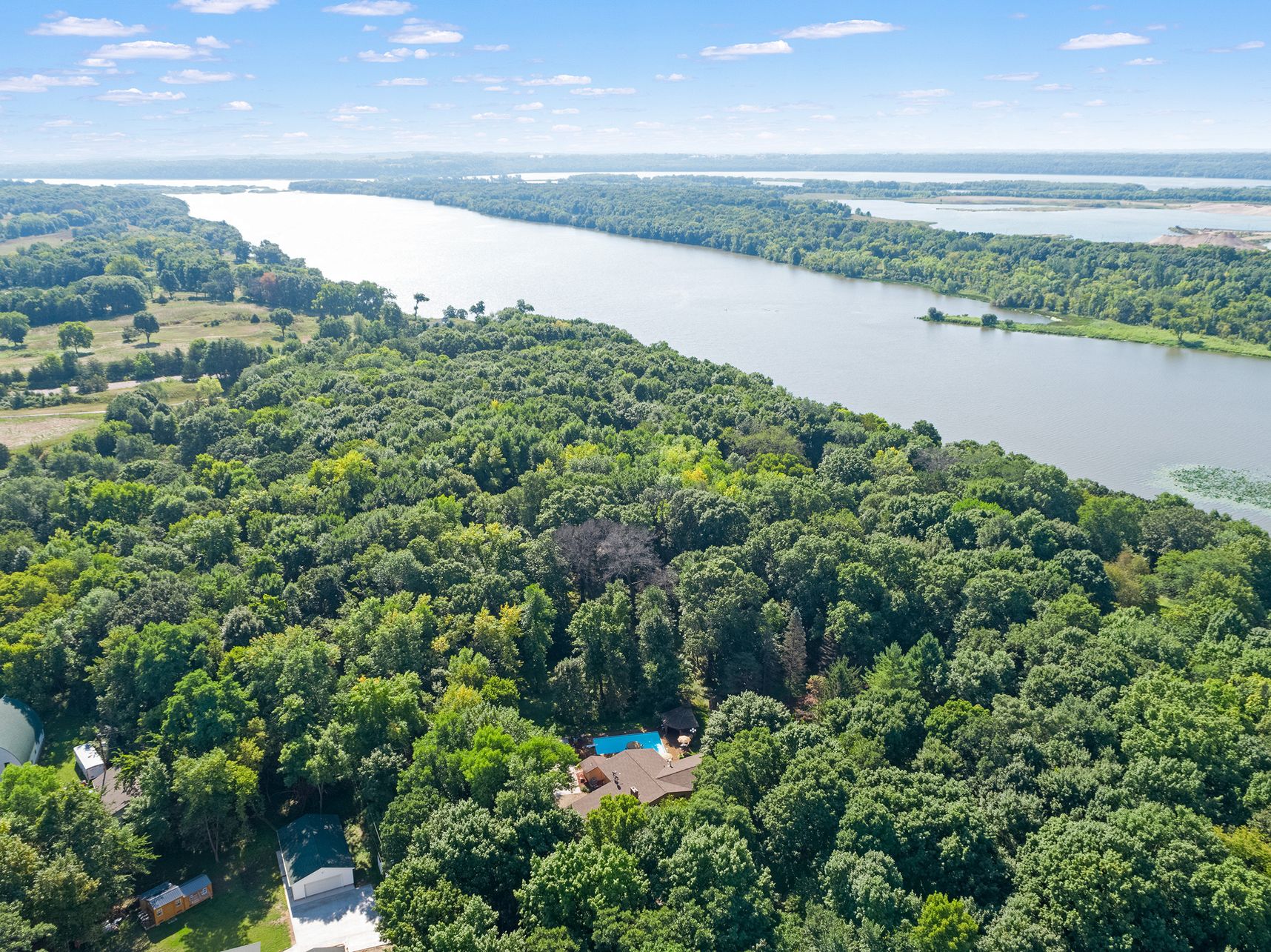 Aerial view of 10651 Grey Cloud Trail S in Cottage Grove, a wooded 2.45-acre lot with a pool, running to the Mississippi River