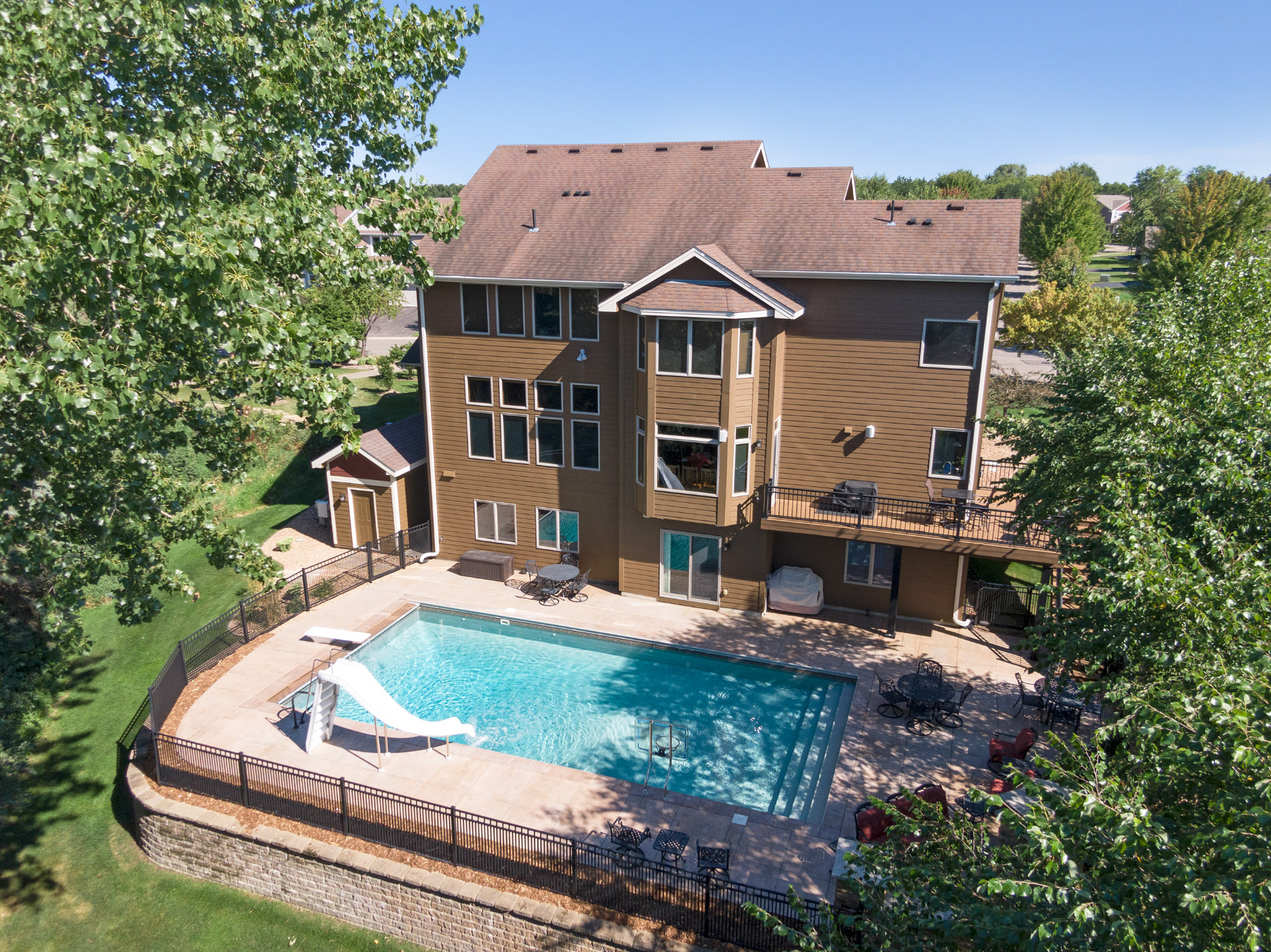Aerial view of a two-story home with a backyard swimming pool and deck in the Dancing Waters community of Woodbury, Minnesota