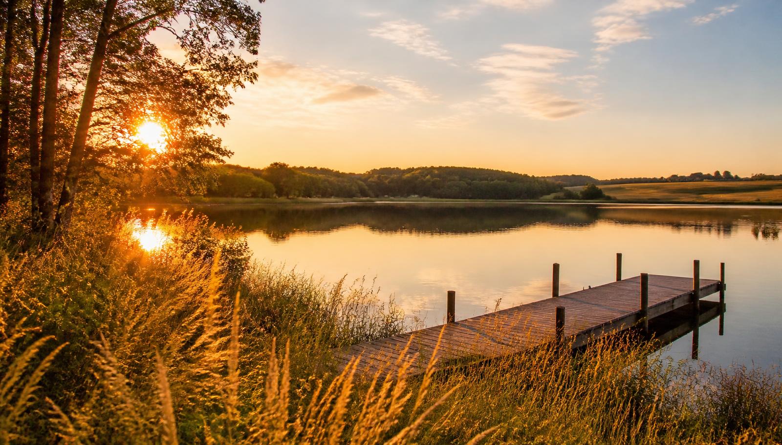 Golden hour over a quiet lake in Lake Elmo, Minnesota, with prairie grasses and a wooden dock